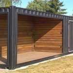 Groene demontabele container als tuinhuis met open deur, stellingplanken en oprijplaat voor opslag in tuin