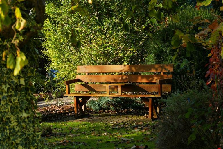 Steigerhouten tuinbank met natuurlijke patinalaag in een tuin