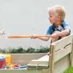 Kind speelt in zandbak voor in de tuin met speelgoed en zand