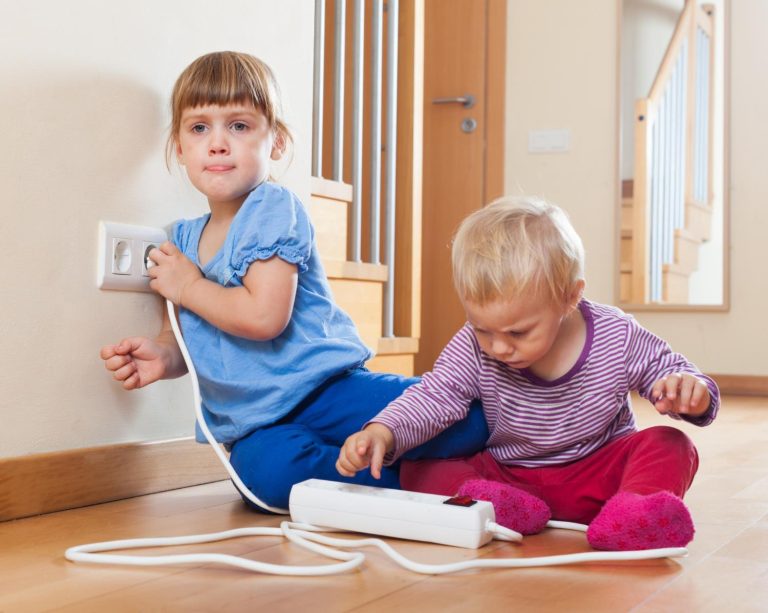 Kind bereikt naar stopcontact als voorbeeld van stekkerveiligheid risico's voor kinderen in huis