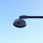Moderne outdoor douche met strakke lijnen en RVS materiaal in een stijlvolle tuinomgeving met groene beplanting